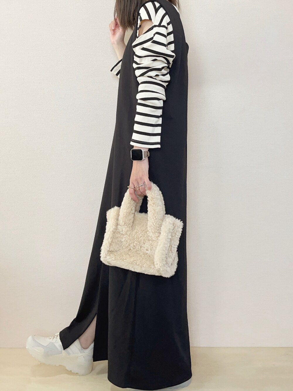 ブラック系のジャンパースカート、ホワイト系のスニーカーを着用したレディースの秋コーディネートの3枚目の写真