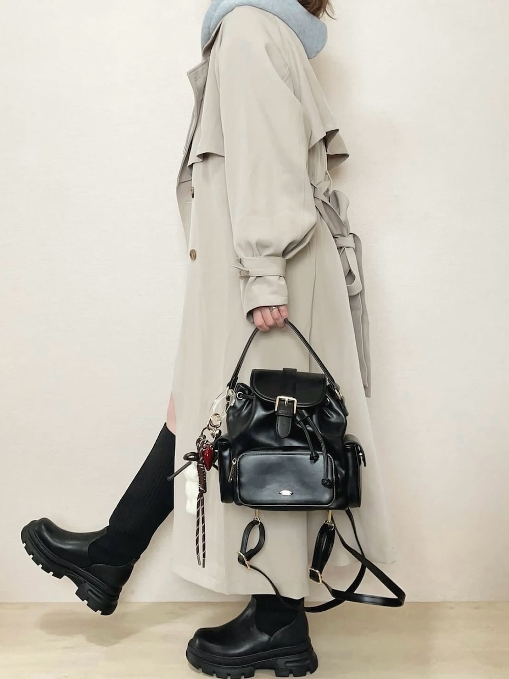 ベージュ系のトレンチコート、グレー系のパーカー、ブラック系のブーツを着用したレディースの冬コーディネートの3枚目の写真