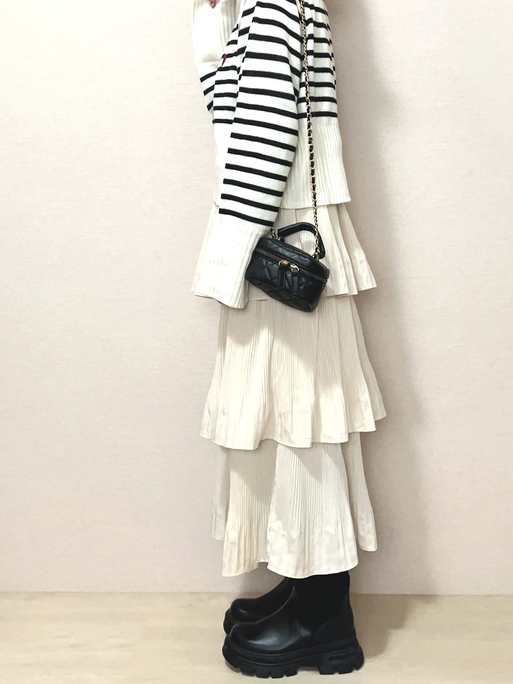 ホワイト系のニット/セーター、ベージュ系のスカート、ブラック系のブーツを着用したレディースの冬コーディネートの2枚目の写真
