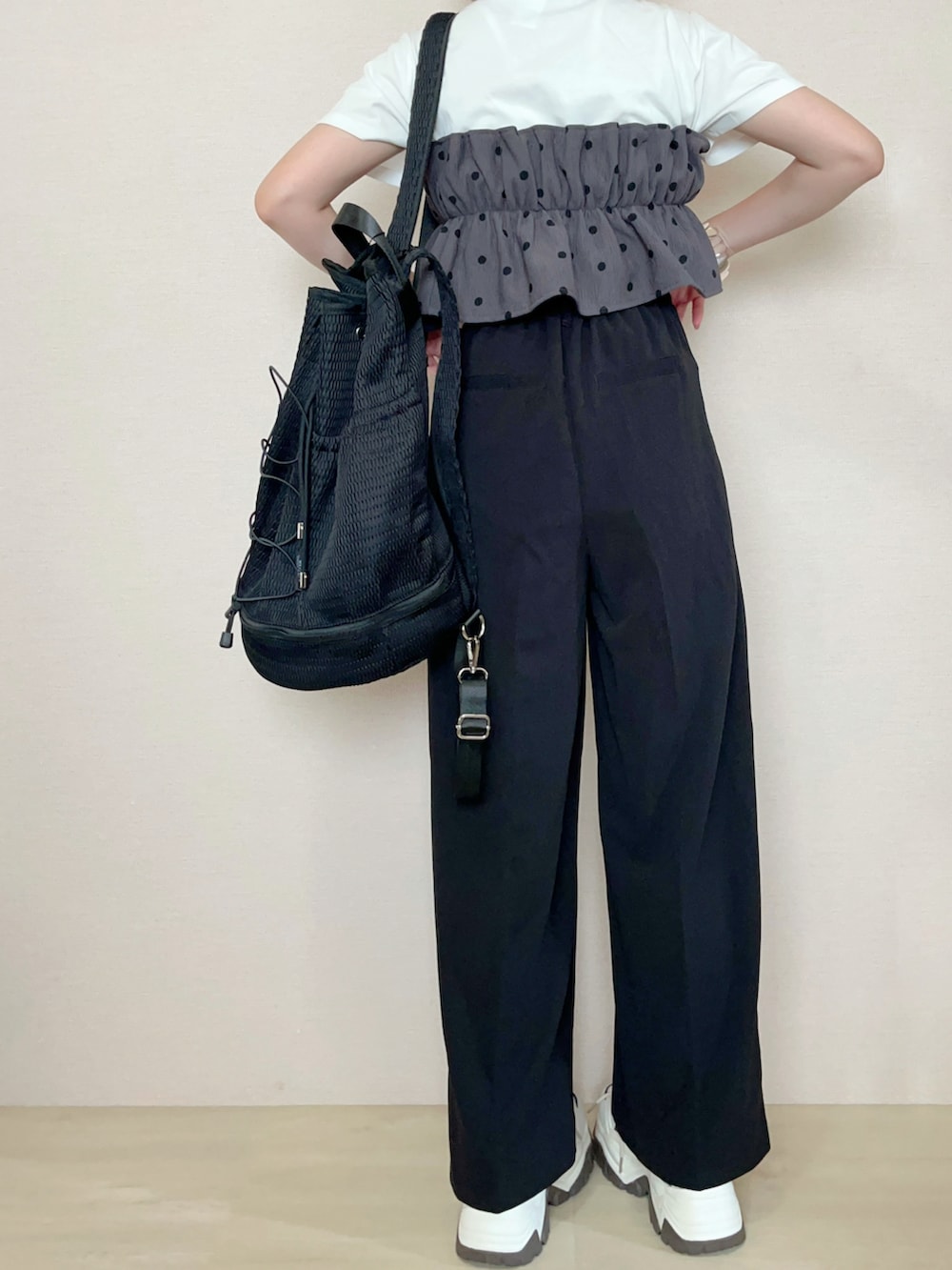 ブラック系のスラックス、ブラック系のバックパック/リュック、ホワイト系のTシャツ/カットソーを着用したレディースの夏コーディネートの3枚目の写真