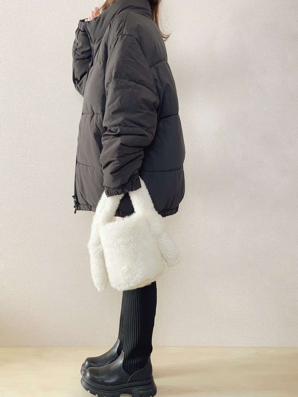 ブラック系のダウンジャケット/コート、ホワイト系のTシャツ/カットソー、ブラック系のブーツを着用したレディースの秋コーディネートの3枚目の写真