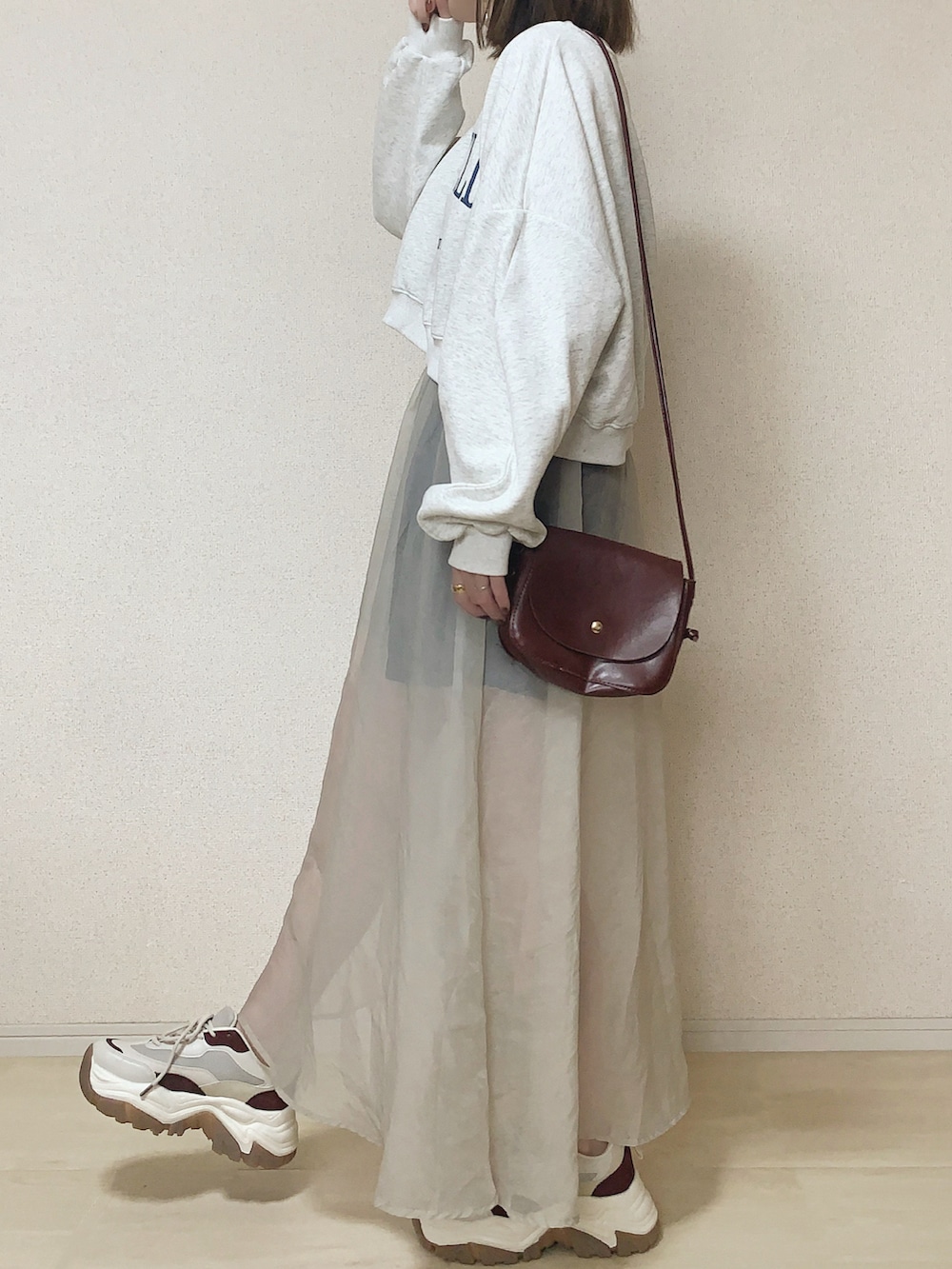 ベージュ系のスウェット、ベージュ系のワンピース、ブラウン系のショルダーバッグを着用したレディースの春コーディネートの2枚目の写真