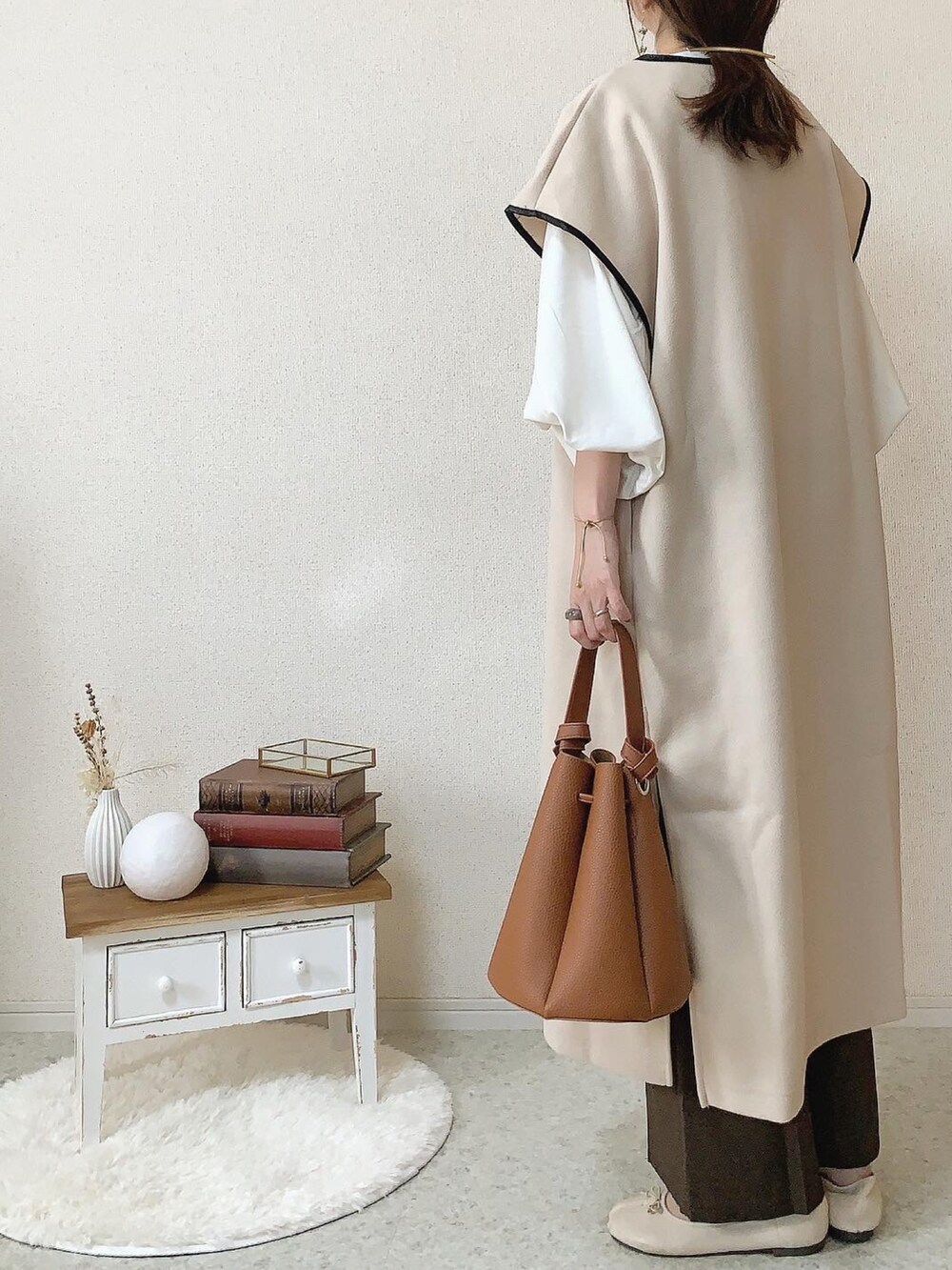 ホワイト系のベスト、ホワイト系のバレエシューズ、ブラウン系のパンツを着用したレディースの秋コーディネートの2枚目の写真