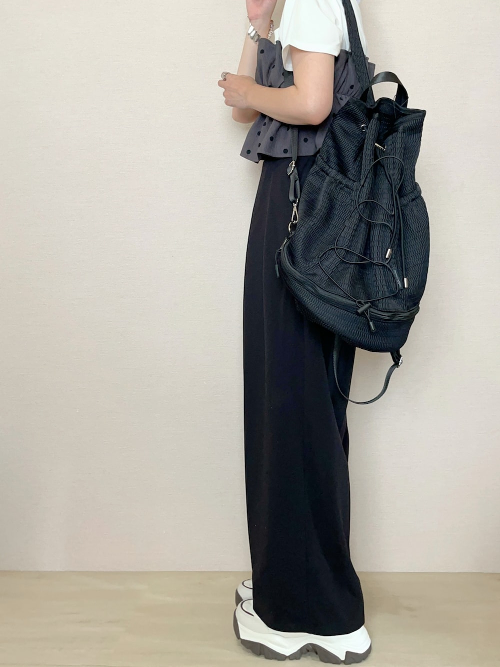 ブラック系のスラックス、ブラック系のバックパック/リュック、ホワイト系のTシャツ/カットソーを着用したレディースの夏コーディネートの2枚目の写真