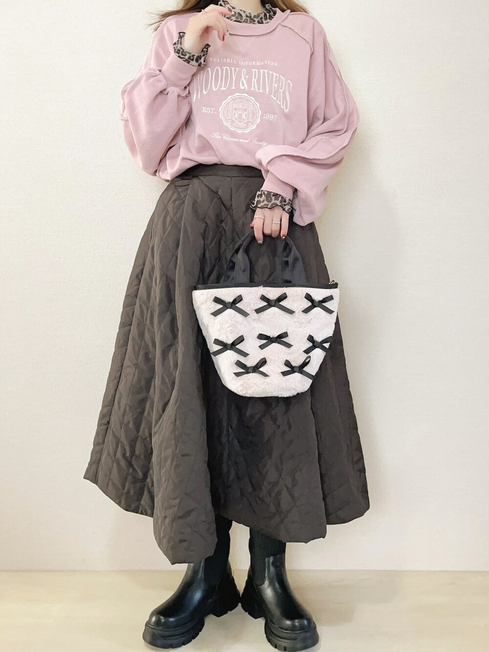 ピンク系のスウェット、ブラウン系のスカート、ブラック系のブーツを着用したレディースの冬コーディネートの2枚目の写真