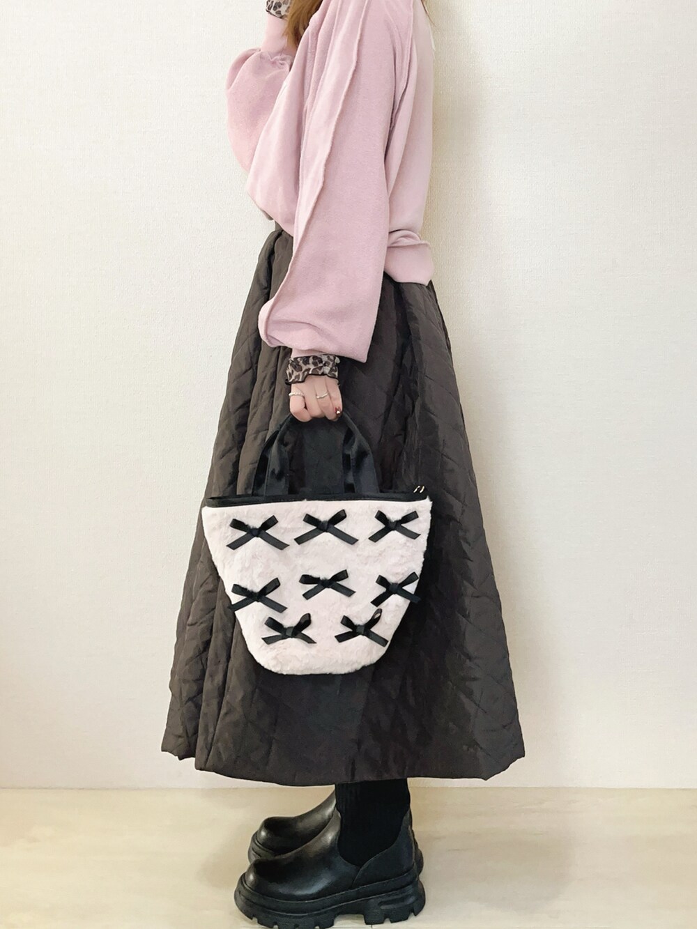 ピンク系のスウェット、ブラウン系のスカート、ブラック系のブーツを着用したレディースの冬コーディネートの3枚目の写真