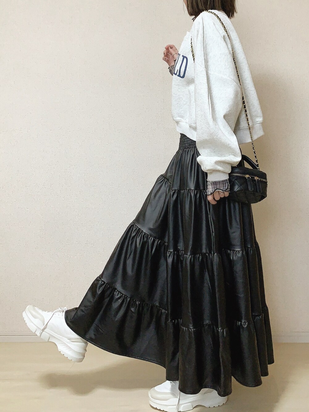 ブラック系のスカート、ベージュ系のスウェット、グレー系のTシャツ/カットソーを着用したレディースの春コーディネートの2枚目の写真