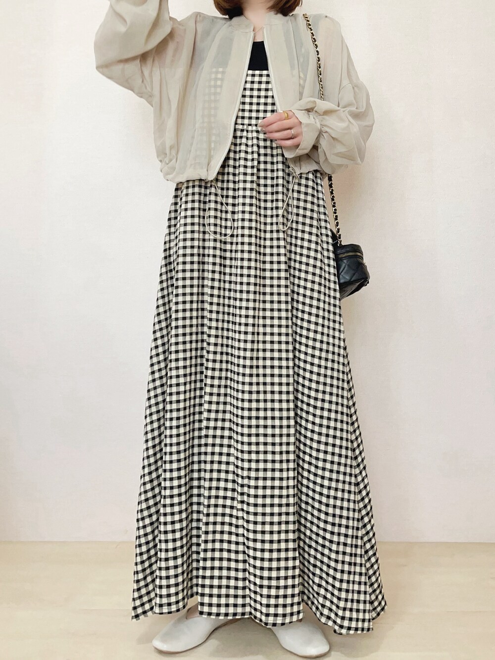 ベージュ系のブルゾン、ブラック系のワンピースを着用したレディースの春コーディネートの2枚目の写真