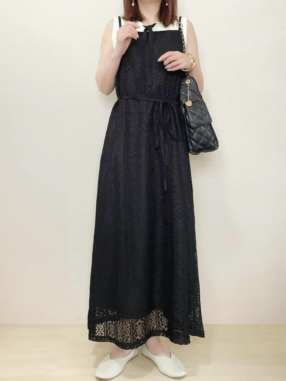 ブラック系のワンピース、ブラック系のショルダーバッグを着用したレディースの春コーディネートの2枚目の写真