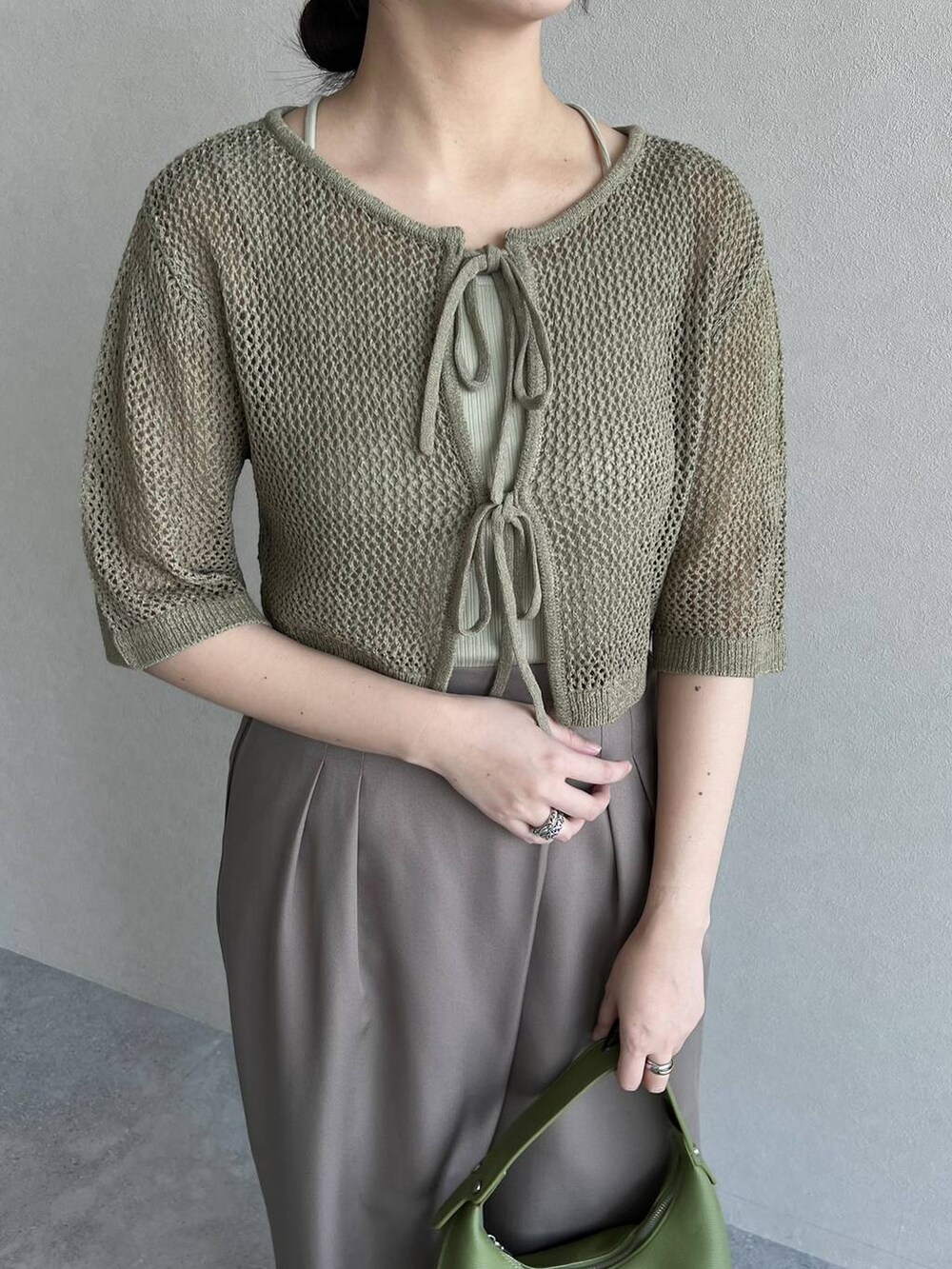 ブラウン系のパンプス、ブラウン系のスラックス、グリーン系のショルダーバッグを着用したレディースの春コーディネートの3枚目の写真