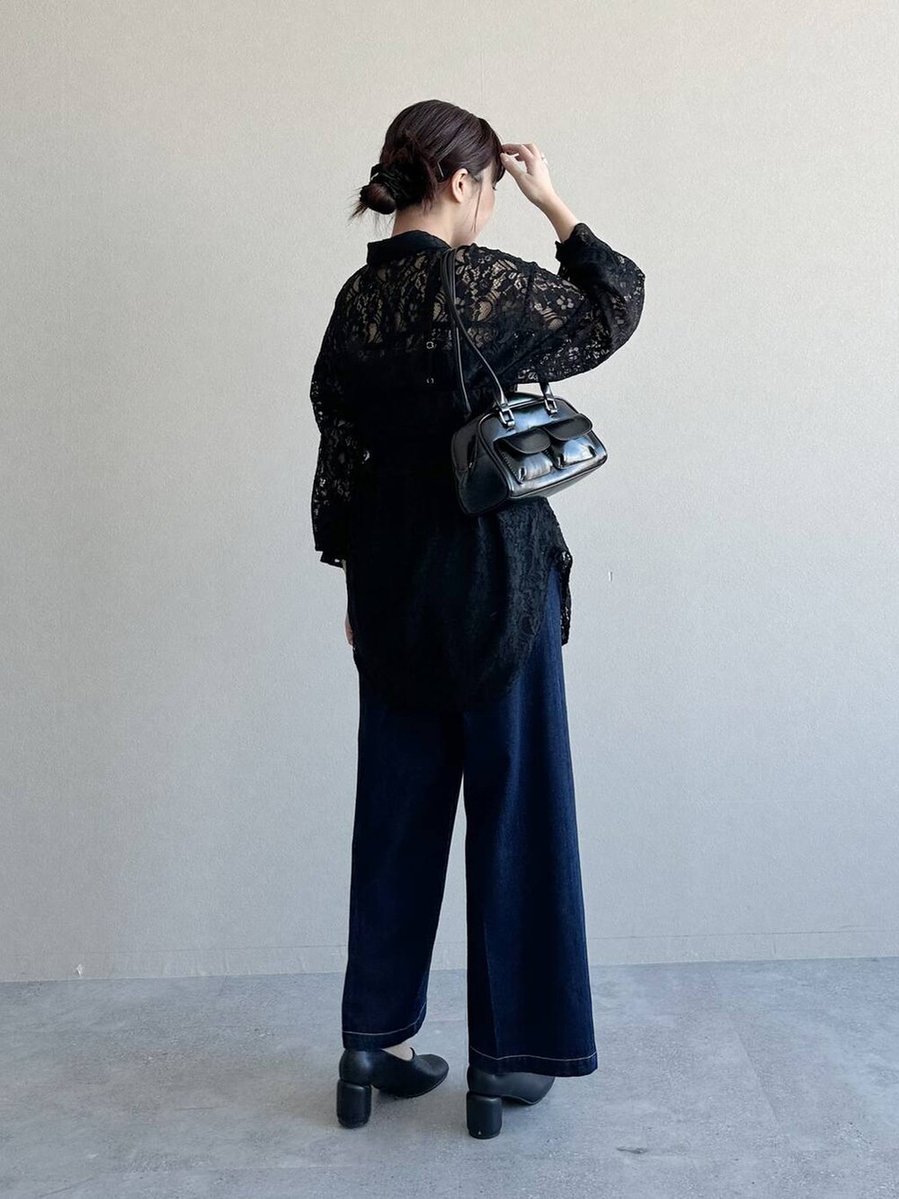 ブラック系のハンドバッグ、ブラック系のパンプス、ブルー系のデニムパンツを着用したレディースの冬コーディネートの2枚目の写真