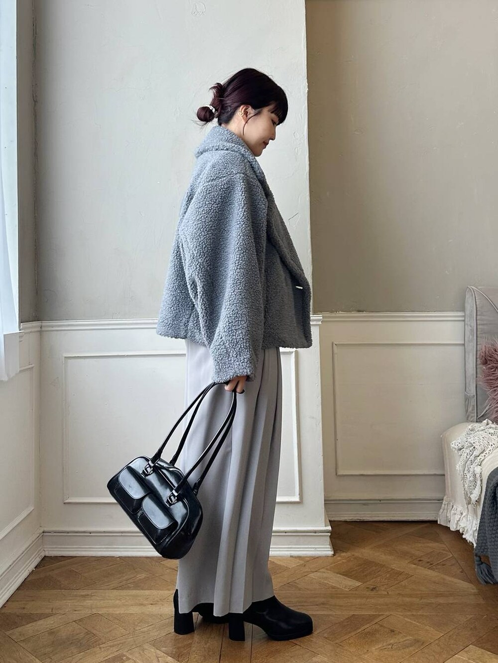 グレー系のピーコート、ブラック系のブーツ、ブルー系のTシャツ/カットソーを着用したレディースの秋コーディネートの2枚目の写真