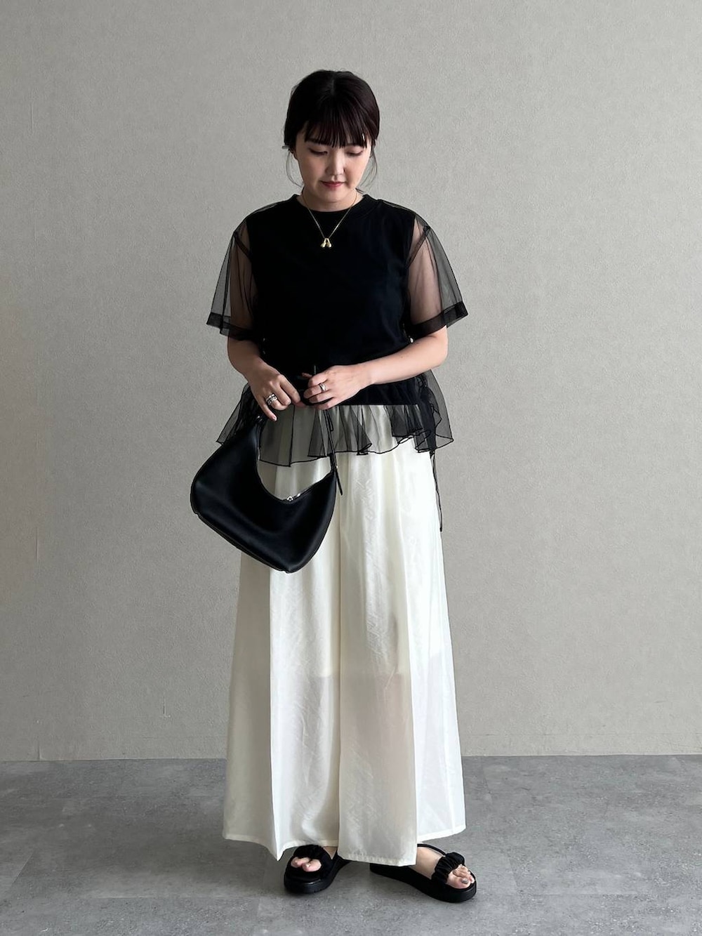 ブラック系のサンダル、ブラック系のショルダーバッグ、ブラック系のTシャツ/カットソーを着用したレディースの夏コーディネートの2枚目の写真