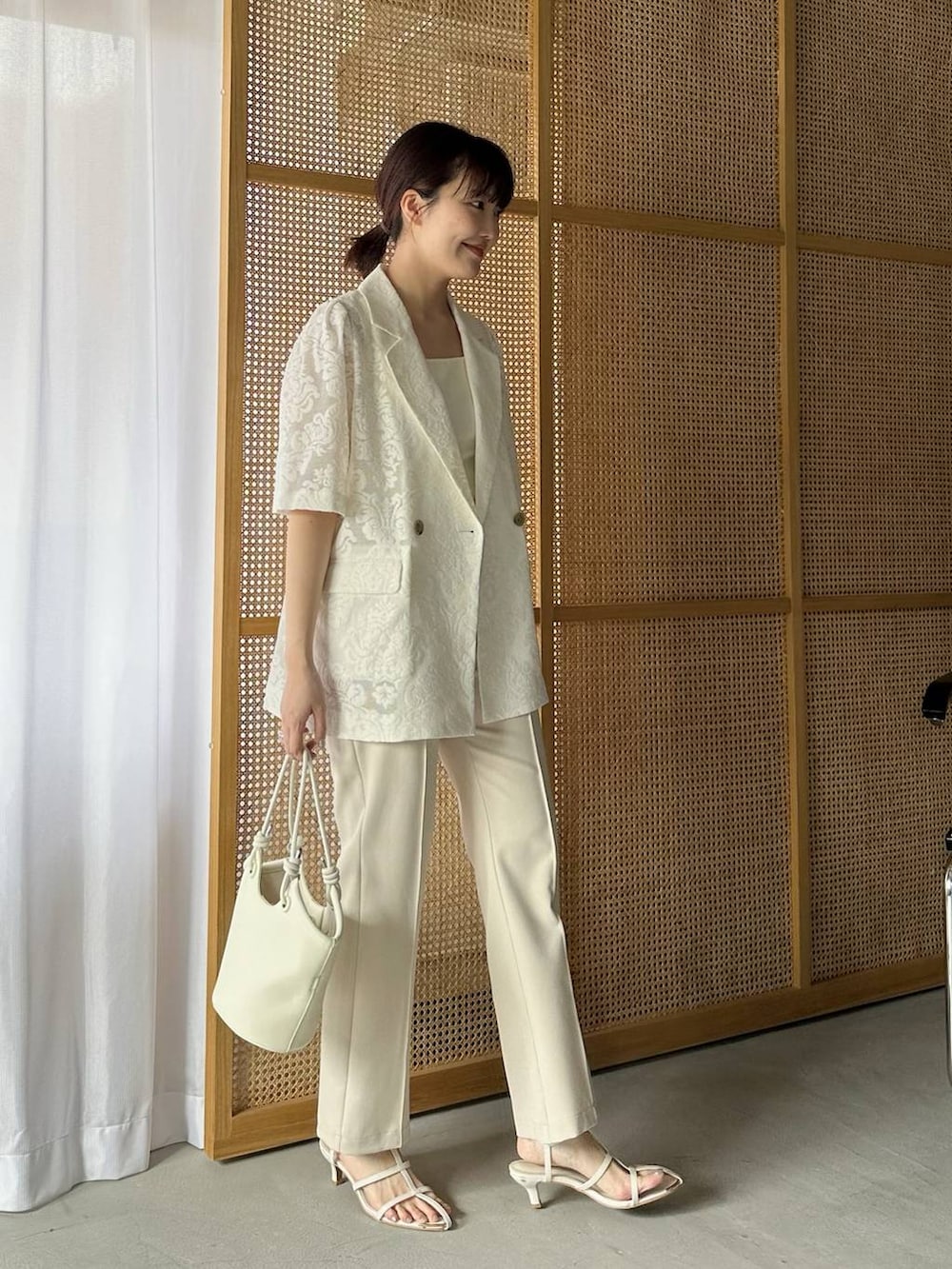 ベージュ系のその他パンツ、ホワイト系のハンドバッグ、ホワイト系のタンクトップを着用したレディースの春コーディネートの3枚目の写真