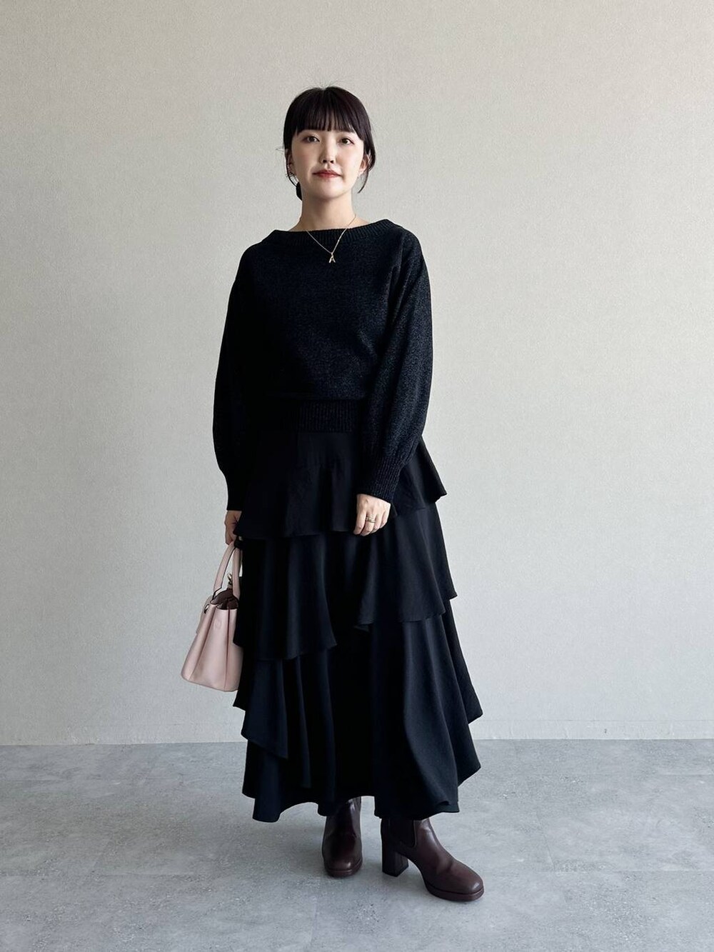 ブラック系のブーツ、ブラック系のスカート、ピンク系のショルダーバッグを着用したレディースの冬コーディネートの3枚目の写真