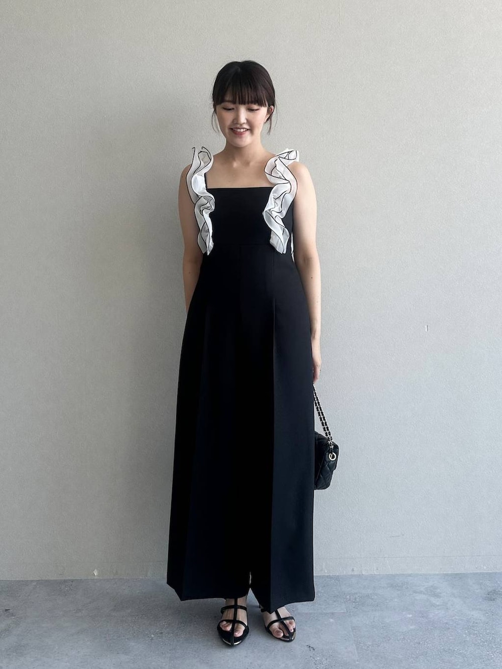 ブラック系のサロペット/オーバーオール、ブラック系のショルダーバッグ、ブラック系のサンダルを着用したレディースの夏コーディネートの2枚目の写真