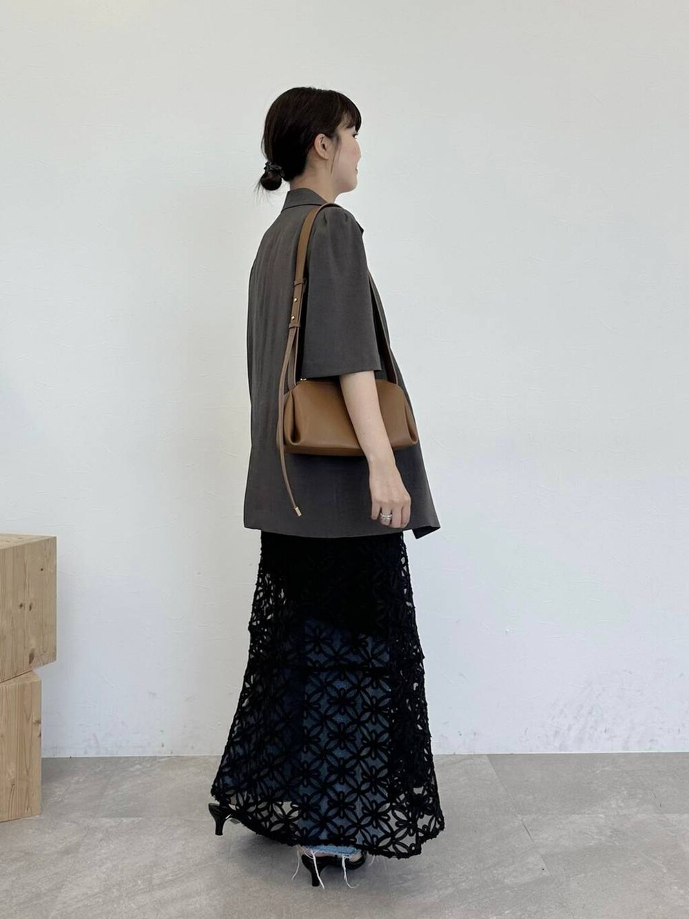 ブラウン系のテーラードジャケット、ブラック系のサンダル、ブラウン系のショルダーバッグを着用したレディースの夏コーディネートの2枚目の写真