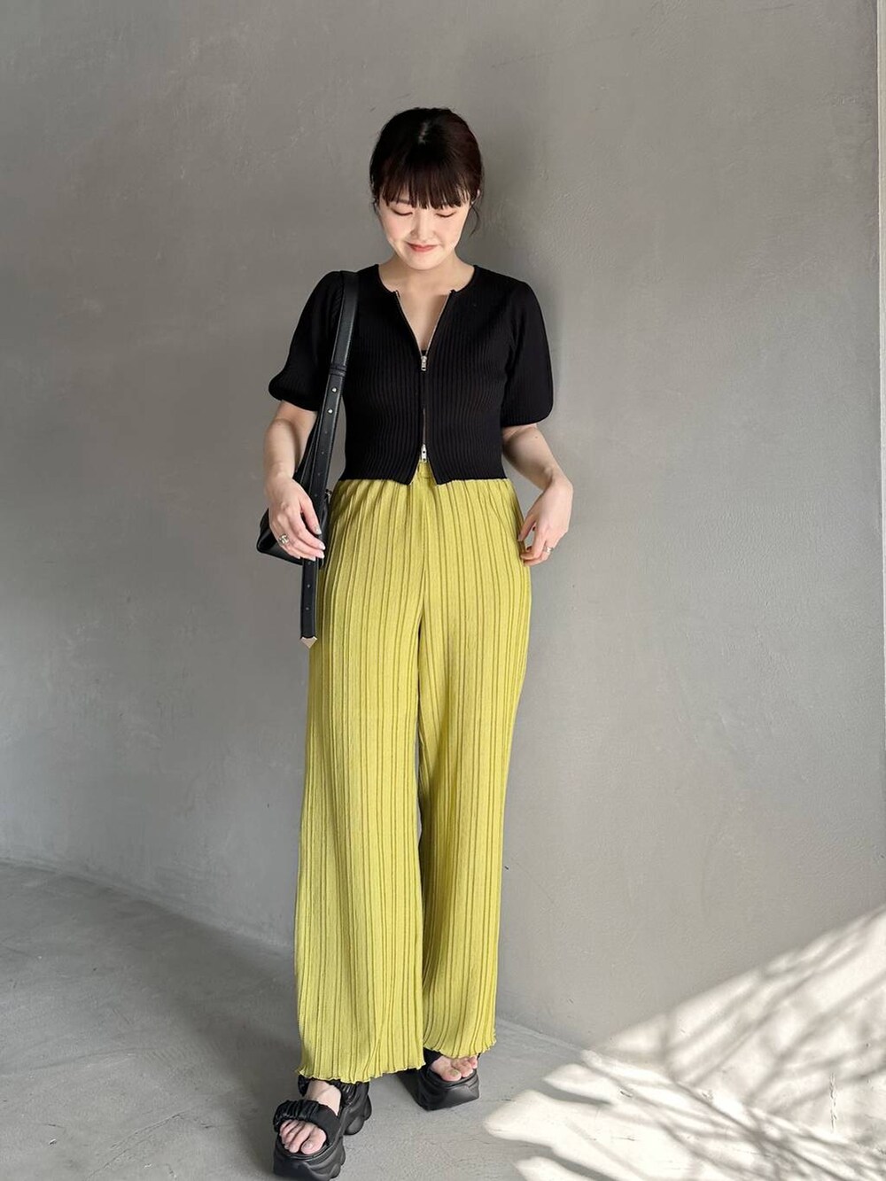 ブラック系のニット/セーター、ブラック系のサンダル、グリーン系のその他パンツを着用したレディースの春コーディネートの2枚目の写真