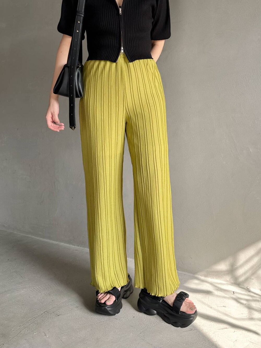 ブラック系のニット/セーター、ブラック系のサンダル、グリーン系のその他パンツを着用したレディースの春コーディネートの4枚目の写真