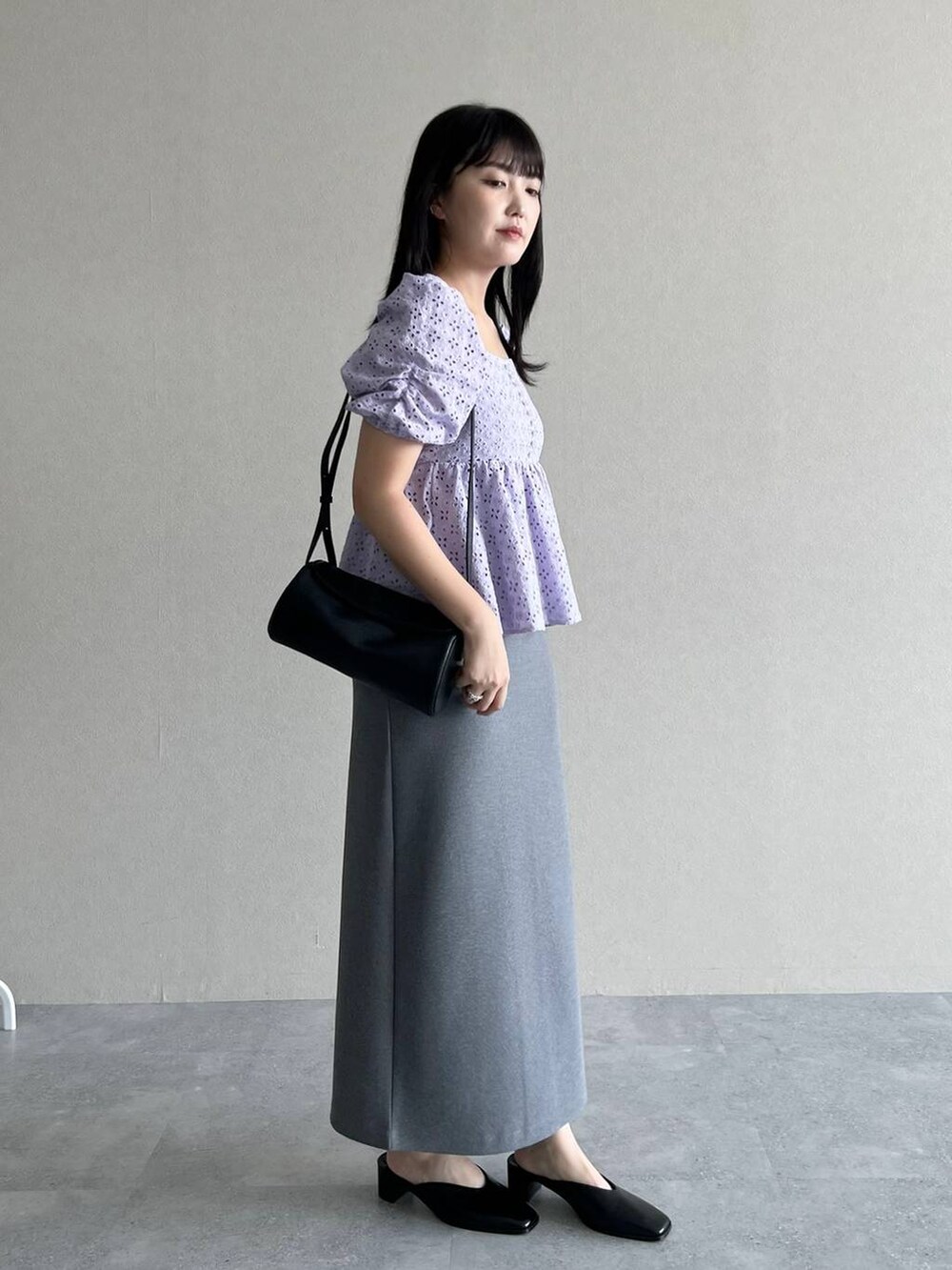 ブラック系のショルダーバッグ、グレー系のスカート、パープル系のシャツ/ブラウスを着用したレディースの夏コーディネートの2枚目の写真