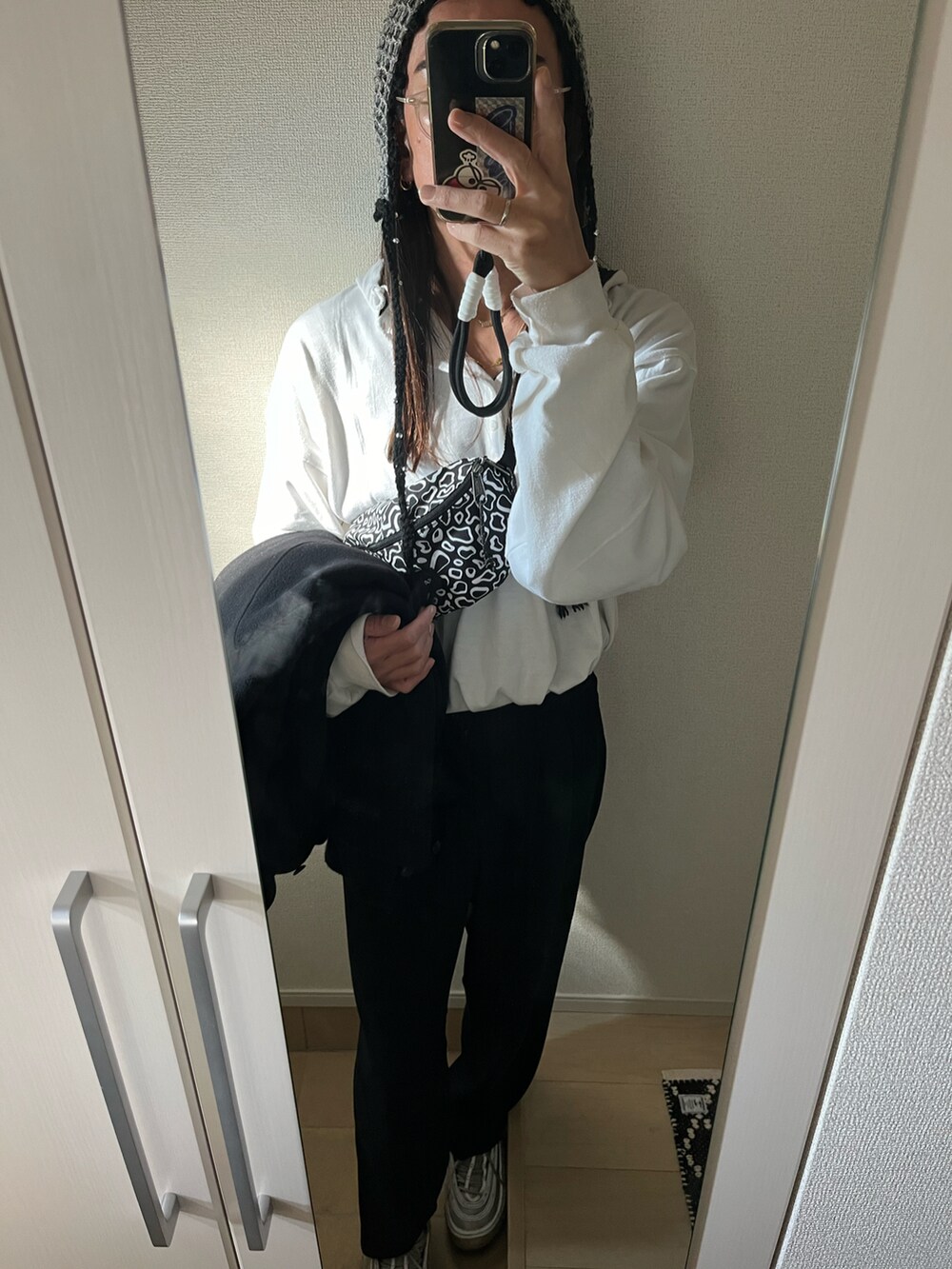 ブラック系のステンカラーコート、ブラック系のボディバッグ/ウエストポーチ、シルバー系のスニーカーを着用したメンズの冬コーディネートの3枚目の写真