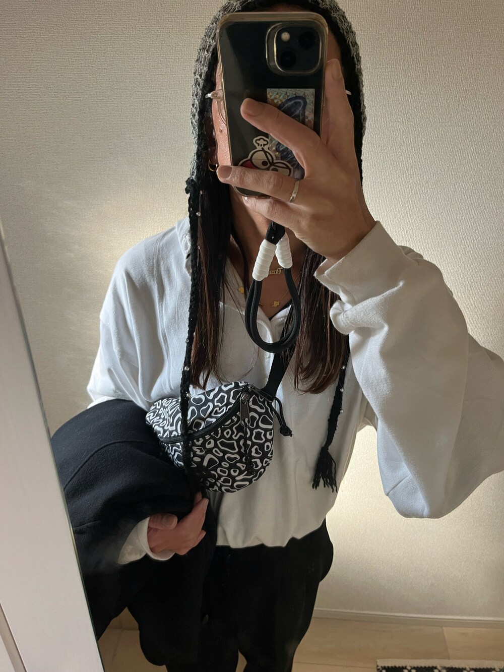 ブラック系のステンカラーコート、ブラック系のボディバッグ/ウエストポーチ、シルバー系のスニーカーを着用したメンズの冬コーディネートの4枚目の写真