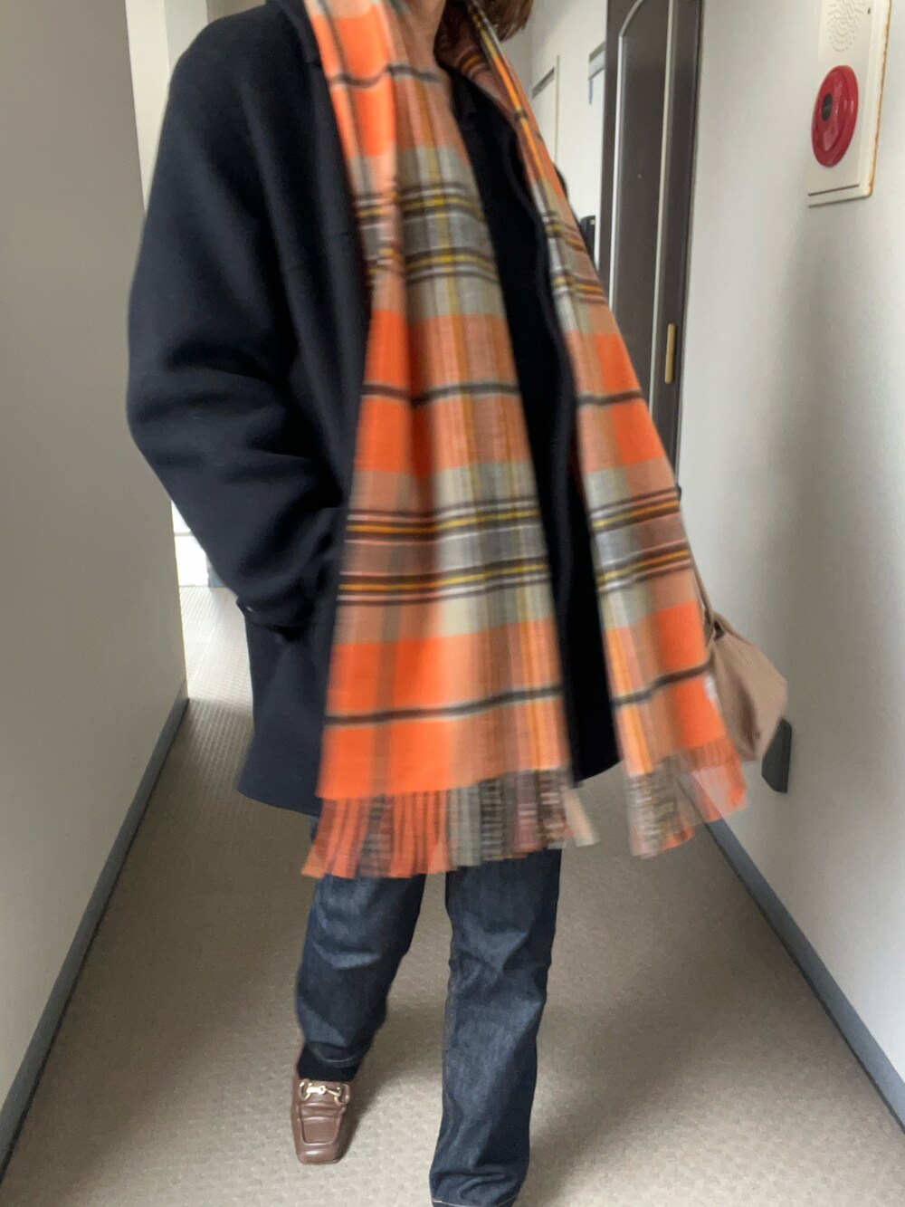 ブラック系のステンカラーコート、その他のデニムパンツを着用したメンズの冬コーディネートの2枚目の写真