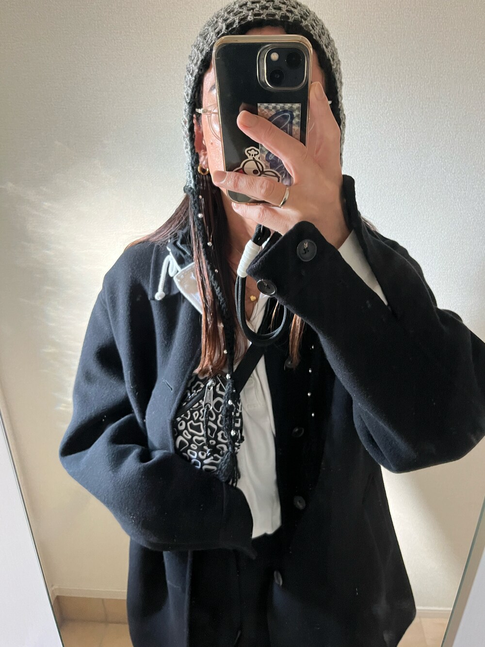 ブラック系のステンカラーコート、ブラック系のボディバッグ/ウエストポーチ、シルバー系のスニーカーを着用したメンズの冬コーディネートの2枚目の写真