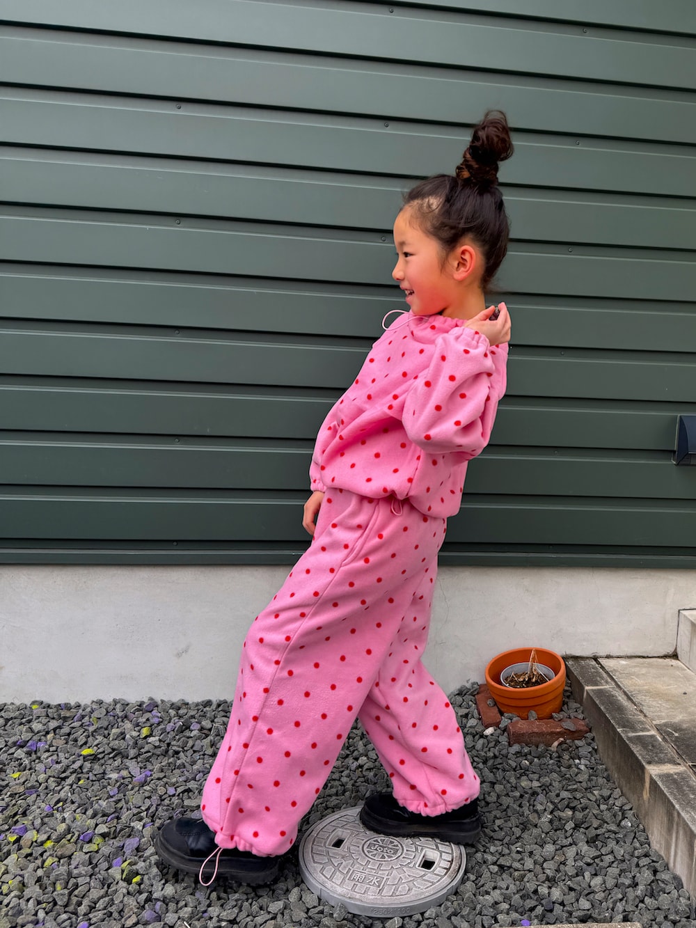 ブラック系のシューズ、ピンク系のオールインワン・サロペットを着用したキッズの冬コーディネートの2枚目の写真