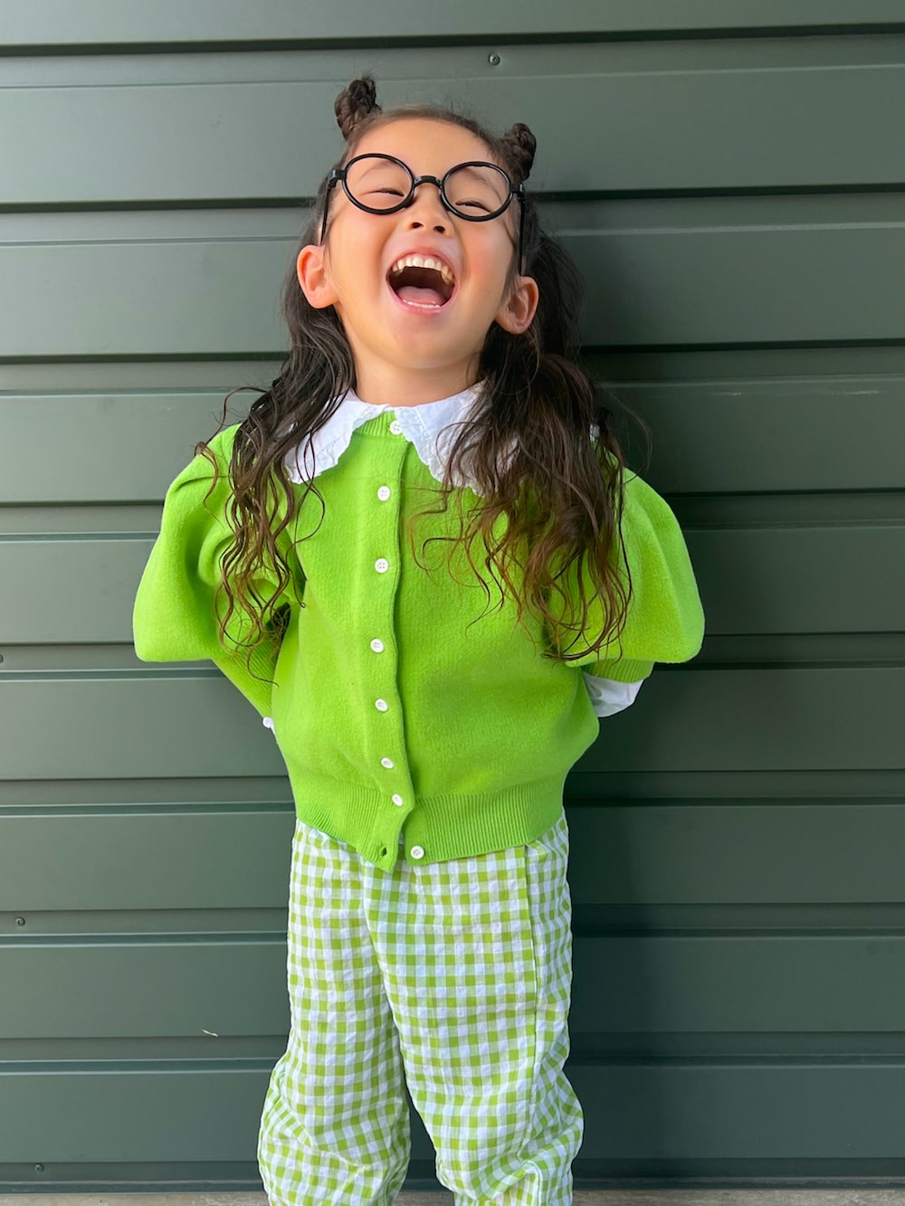 グリーン系のパンツ、ブラック系のシューズ、グリーン系のカーディガン/ボレロを着用したキッズの秋コーディネートの2枚目の写真