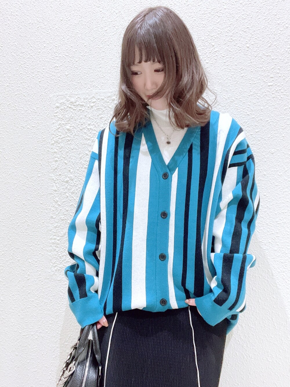 ブルー系のカーディガン/ボレロ、グリーン系のTシャツ/カットソー、ブラック系のショルダーバッグを着用したレディースの冬コーディネートの5枚目の写真
