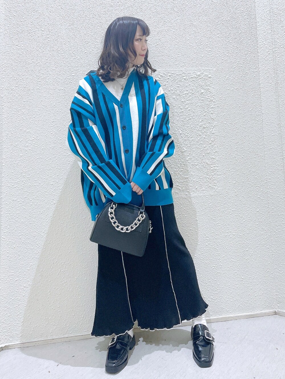 ブルー系のカーディガン/ボレロ、グリーン系のTシャツ/カットソー、ブラック系のショルダーバッグを着用したレディースの冬コーディネートの2枚目の写真