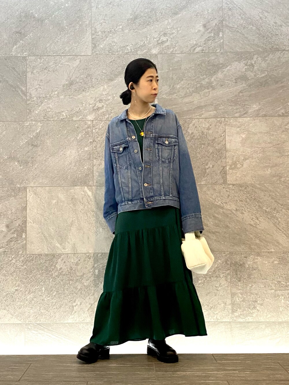 ホワイト系のハンドバッグ、グリーン系のワンピース、ブラック系のブーツを着用したレディースの秋コーディネートの2枚目の写真