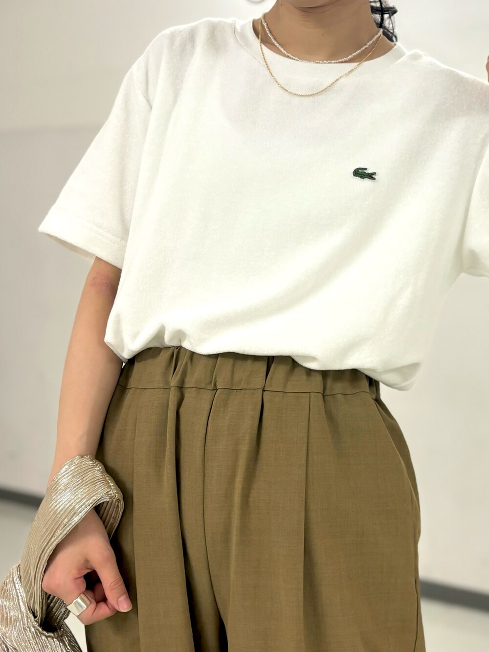 ホワイト系のTシャツ/カットソー、ベージュ系のその他パンツ、ゴールド系のハンドバッグを着用したレディースの夏コーディネートの2枚目の写真