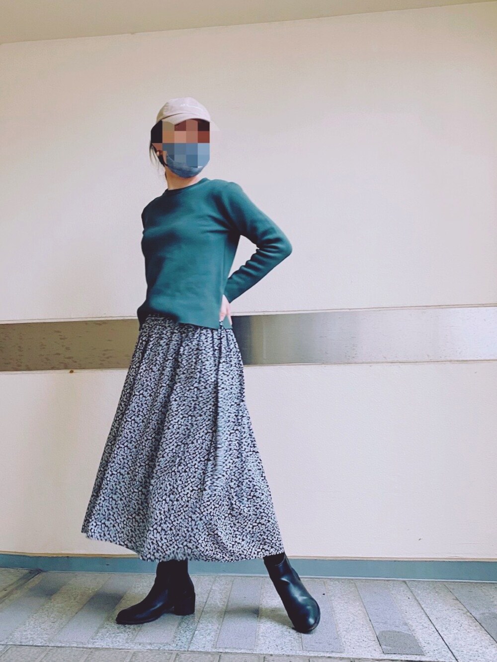 ブラック系のスカート、グリーン系のニット/セーター、ブラック系のブーツを着用したレディースの春コーディネートの2枚目の写真