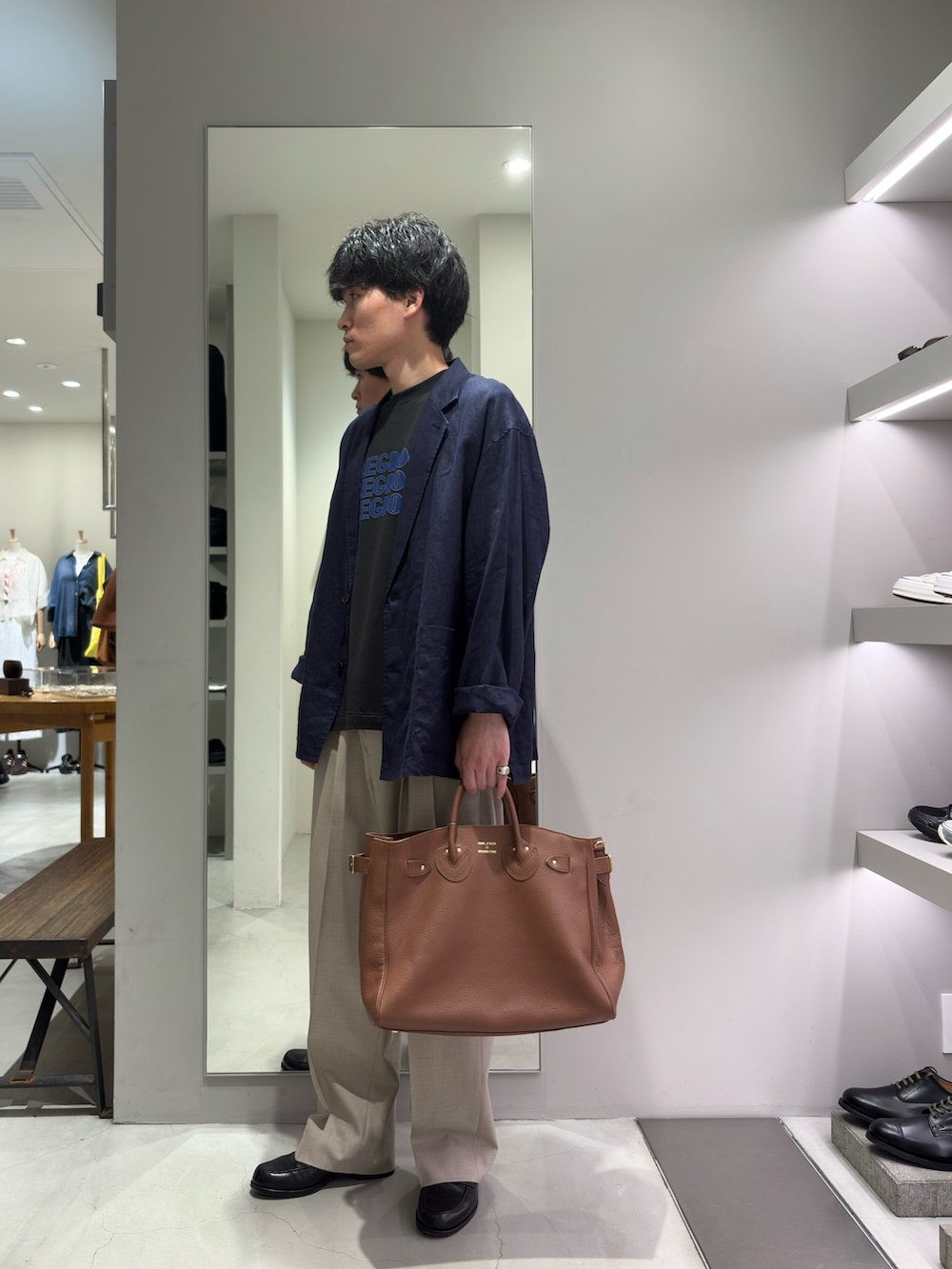ブルー系のその他アウター、ベージュ系のその他パンツ、ブラウン系のトートバッグを着用したメンズの春コーディネートの4枚目の写真