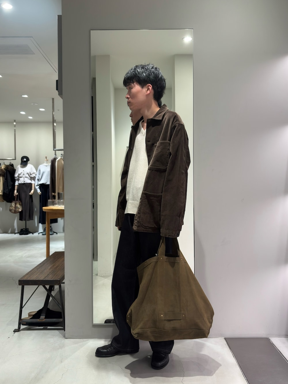 ベージュ系のニット/セーター、グリーン系のトートバッグ、ブルー系のデニムパンツを着用したメンズの秋コーディネートの4枚目の写真