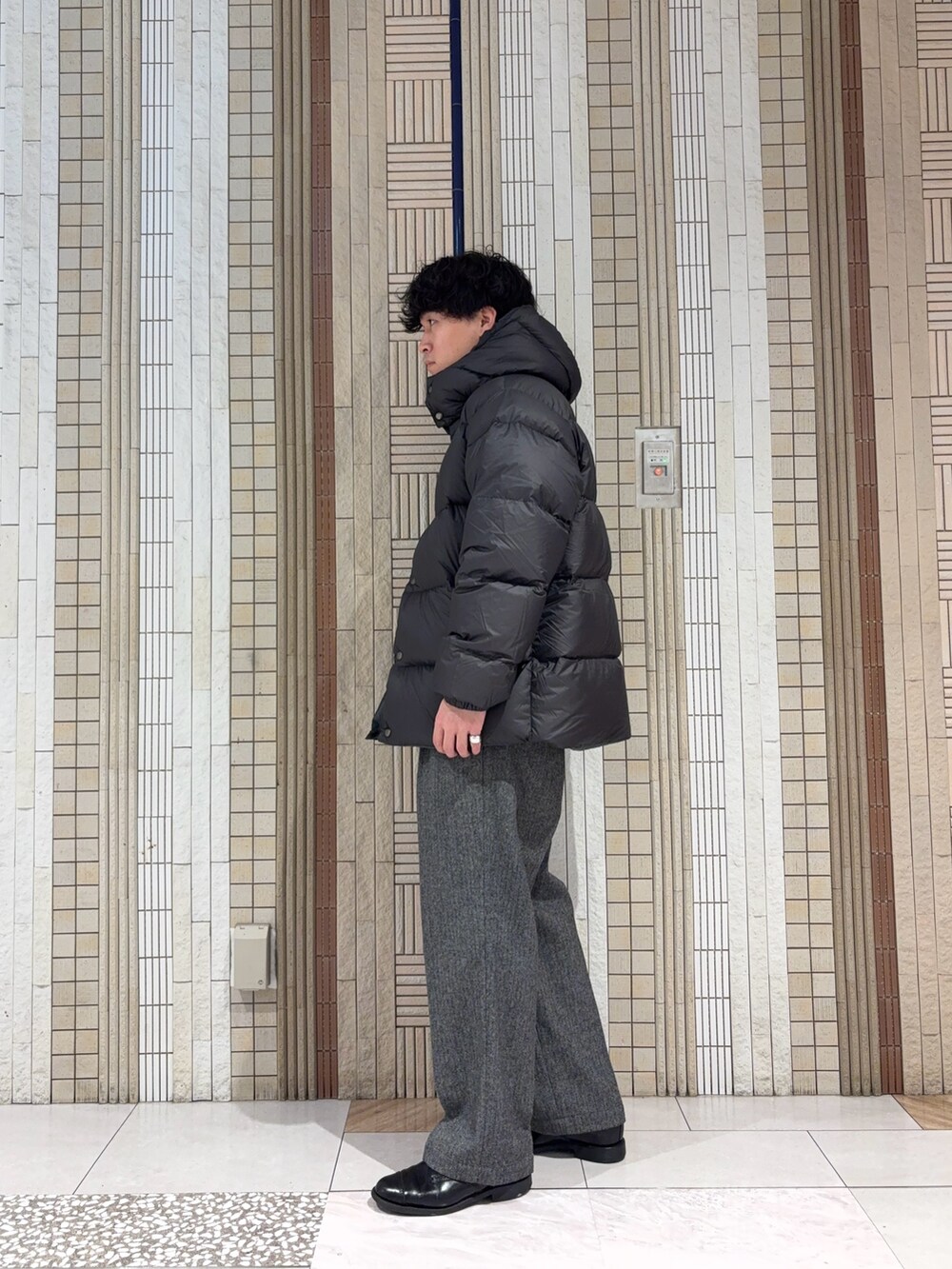 グリーン系のダウンジャケット/コート、ブラック系のニット/セーター、グレー系のその他パンツを着用したメンズの冬コーディネートの6枚目の写真