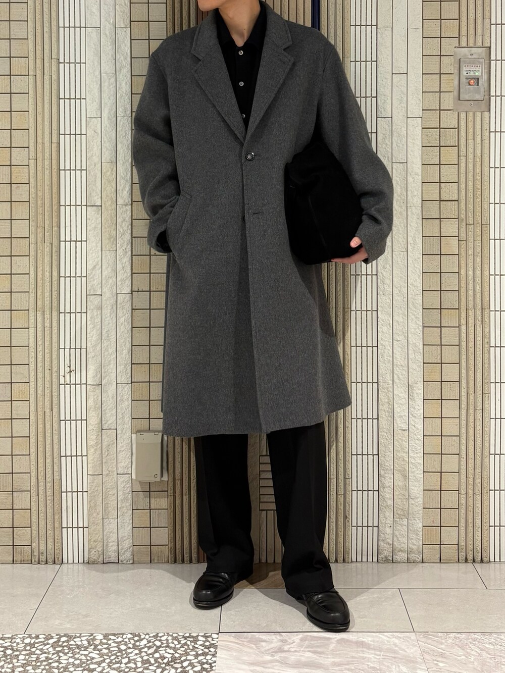 ホワイト系のチェスターコート、グリーン系のトートバッグ、ブラック系のその他パンツを着用したメンズの冬コーディネートの3枚目の写真