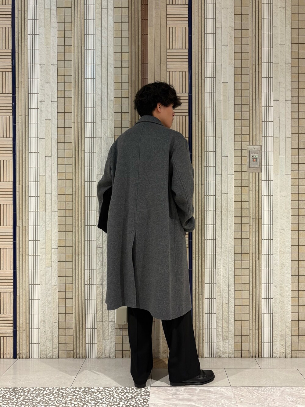 ホワイト系のチェスターコート、グリーン系のトートバッグ、ブラック系のその他パンツを着用したメンズの冬コーディネートの6枚目の写真