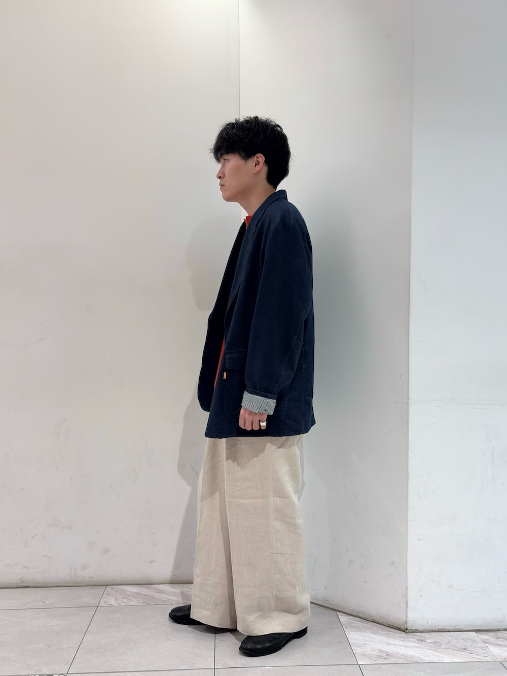 ブルー系のテーラードジャケット、オレンジ系のニット/セーター、ベージュ系のその他パンツを着用したメンズの春コーディネートの4枚目の写真