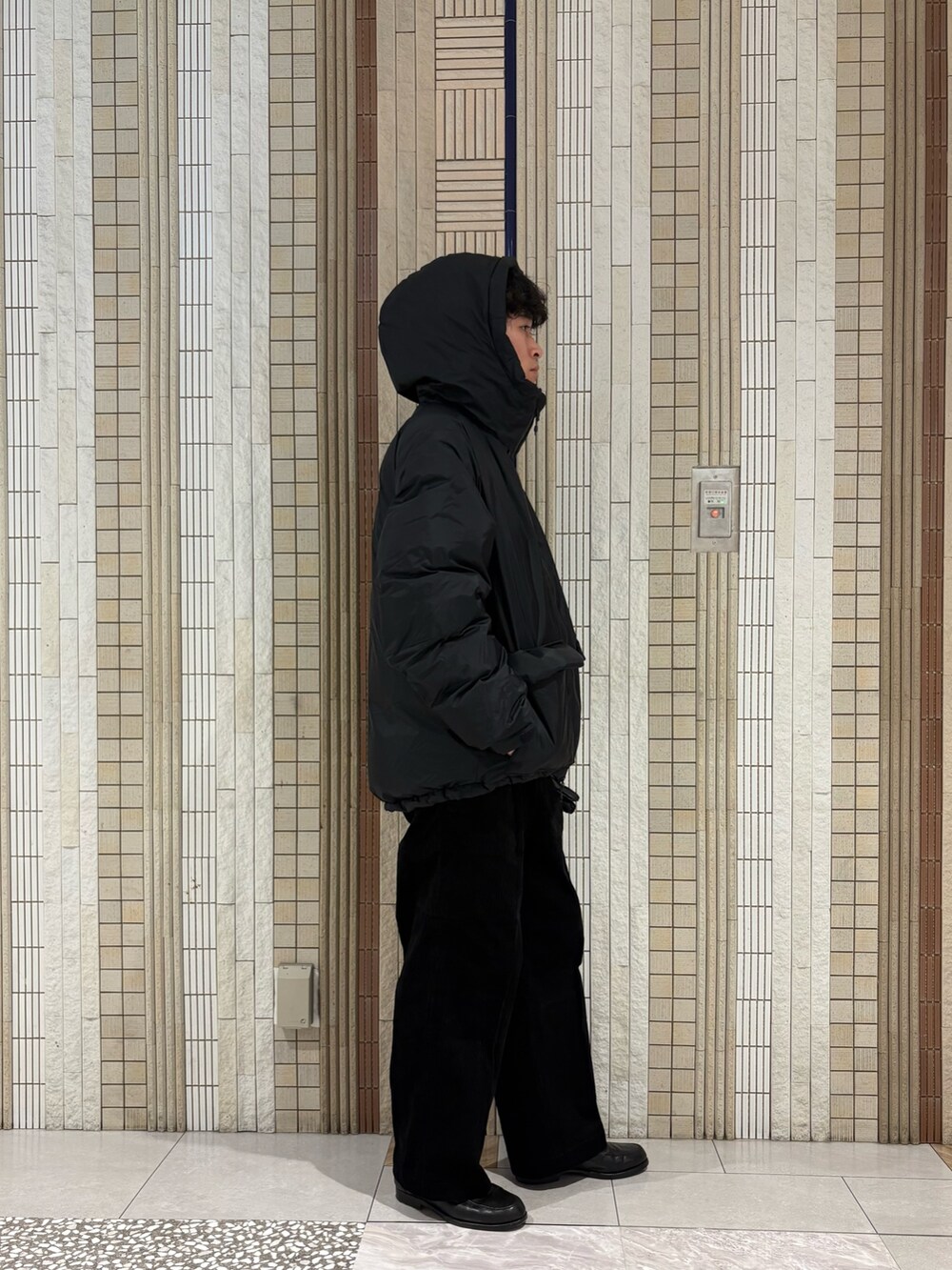 ブラック系のダウンジャケット/コート、グレー系のニット/セーター、ブラック系のその他パンツを着用したメンズの秋コーディネートの7枚目の写真