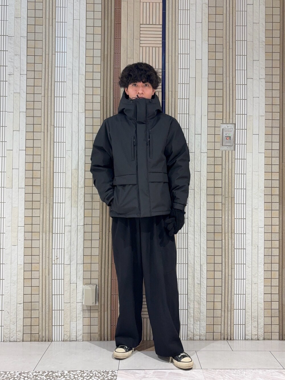 ブラック系のダウンジャケット/コート、グレー系のニット/セーター、ブラック系の手袋を着用したメンズの冬コーディネートの2枚目の写真