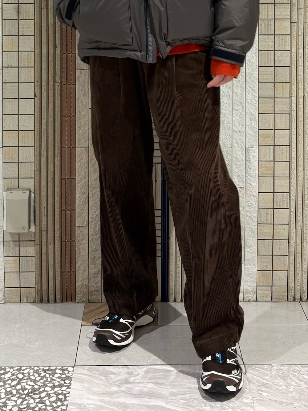 グレー系のダウンジャケット/コート、レッド系のニット/セーター、ブラウン系のその他パンツを着用したメンズの秋コーディネートの4枚目の写真