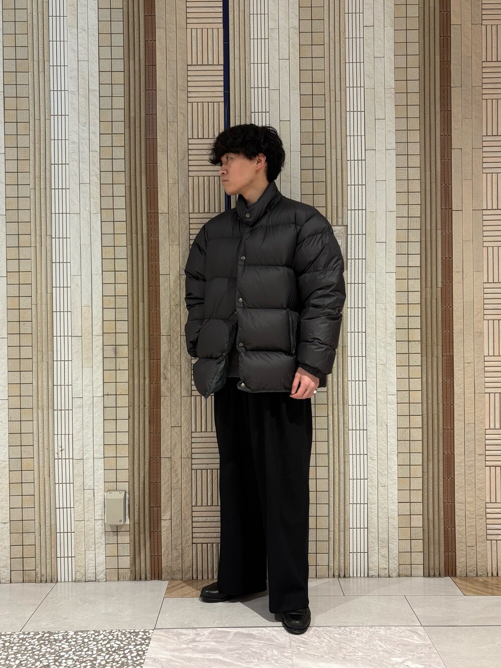 グリーン系のダウンジャケット/コート、グレー系のニット/セーターを着用したメンズの冬コーディネートの2枚目の写真