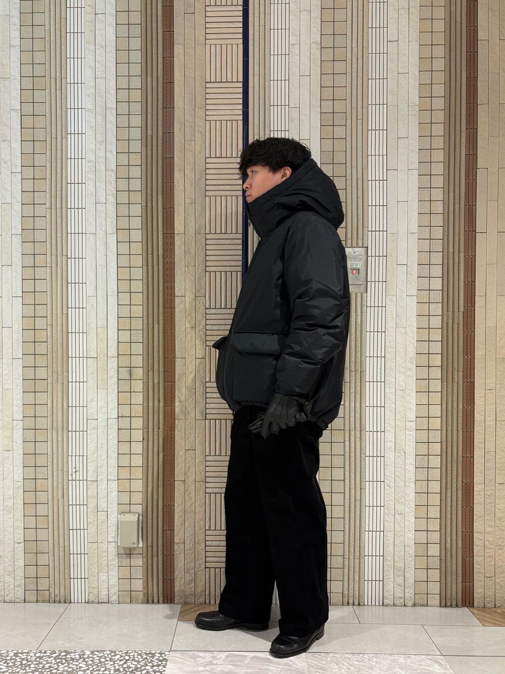 ブラック系のダウンジャケット/コート、グレー系のニット/セーター、ブラック系のその他パンツを着用したメンズの秋コーディネートの8枚目の写真