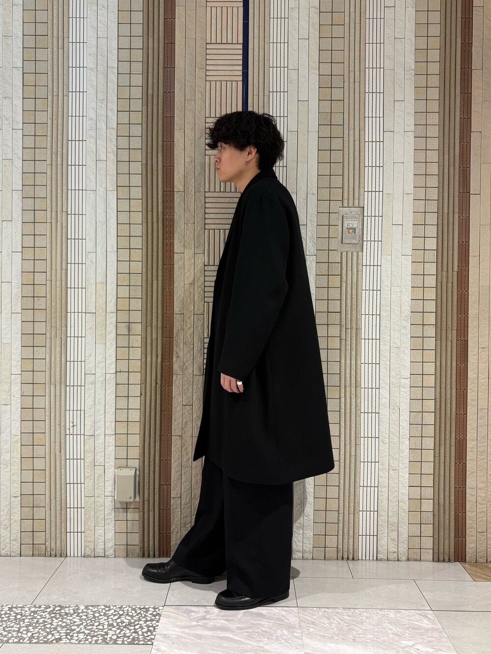 ブラック系のチェスターコート、グレー系のカーディガン/ボレロを着用したメンズの冬コーディネートの6枚目の写真