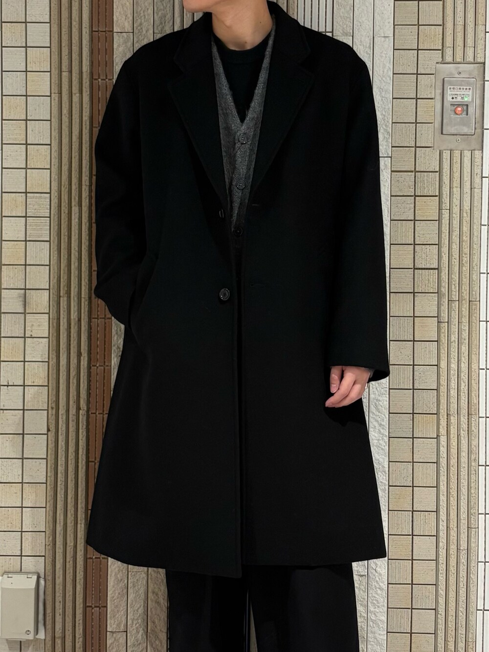 ブラック系のチェスターコート、グレー系のカーディガン/ボレロを着用したメンズの冬コーディネートの5枚目の写真