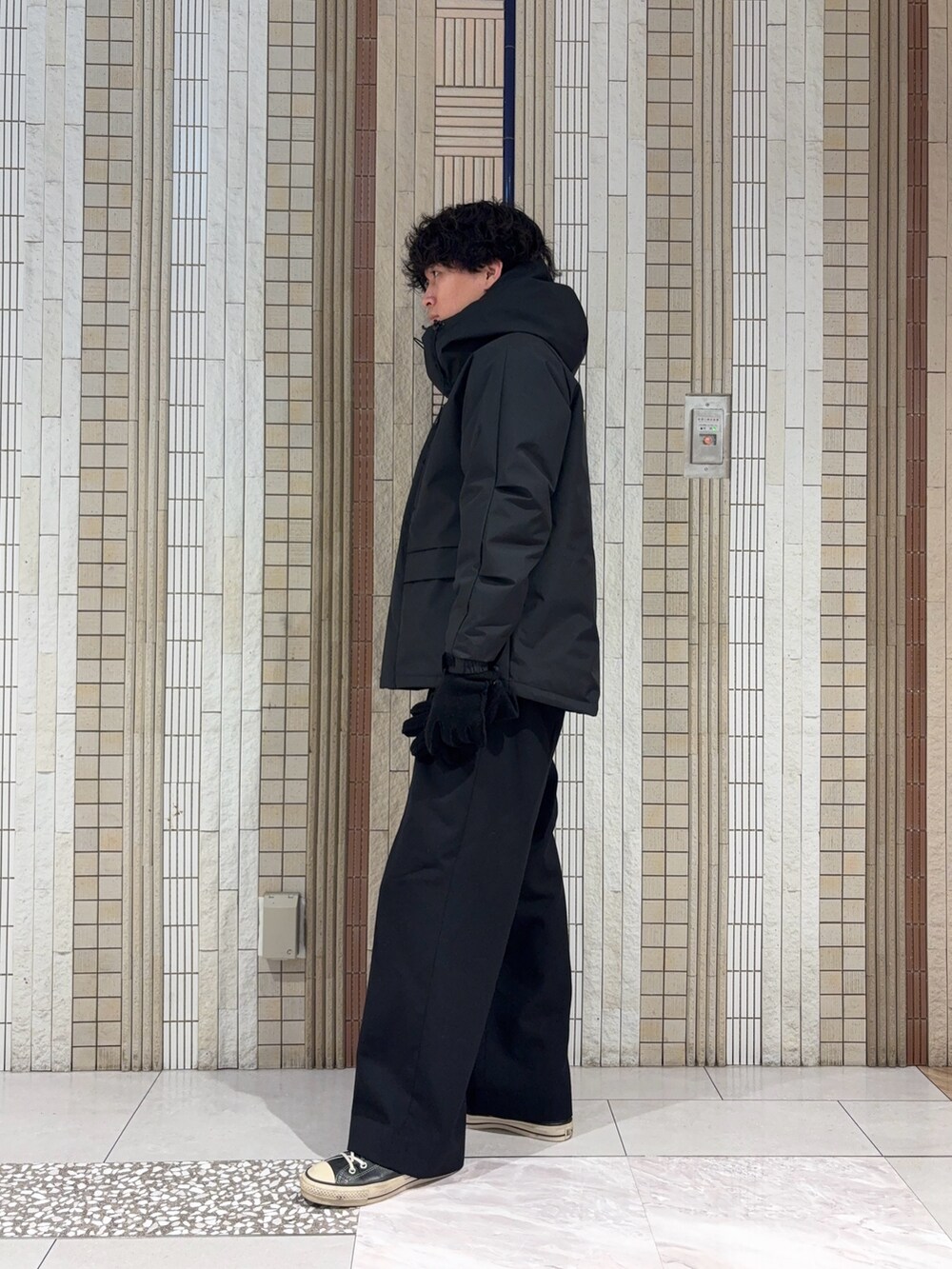 ブラック系のダウンジャケット/コート、グレー系のニット/セーター、ブラック系の手袋を着用したメンズの冬コーディネートの5枚目の写真