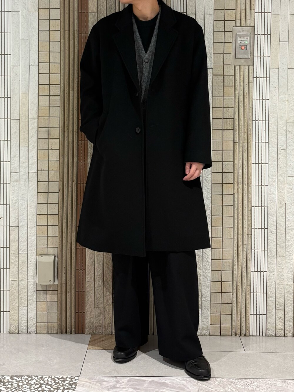 ブラック系のチェスターコート、グレー系のカーディガン/ボレロを着用したメンズの冬コーディネートの4枚目の写真
